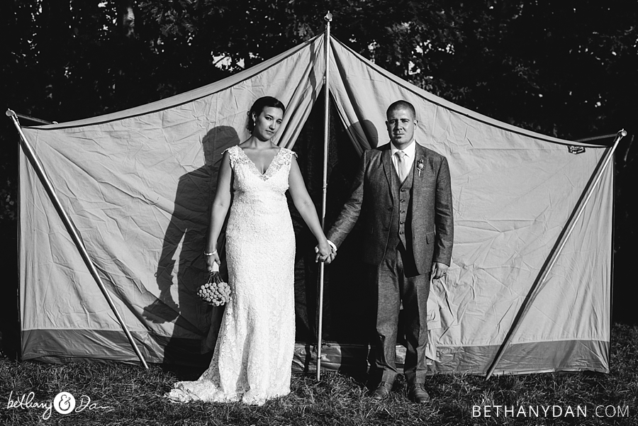 The bride and groom in front of an old tent