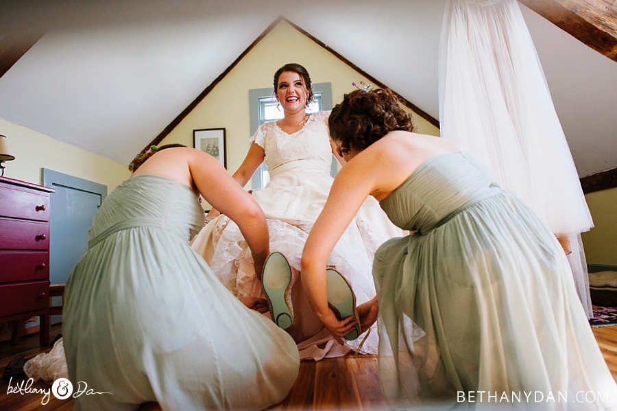 The bridesmaids help the bride get her shoes on